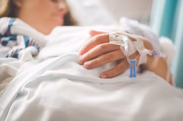 a-woman-laying-in-a-hospital-bed-with-an-iv-in-her-hand
